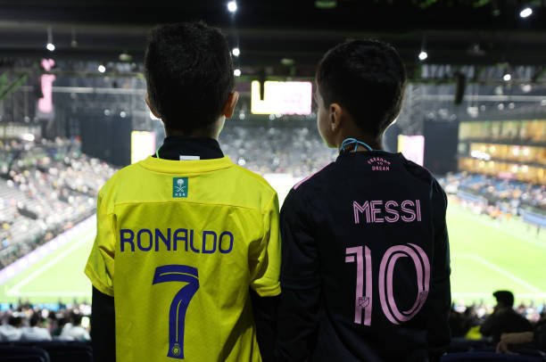 Penggemar Al-Nassr dan Inter Miami berfoto dengan nama Cristiano Ronaldo dan Lionel Messi tercetak di bagian belakang kaos mereka sebelum pertandingan Piala Musim Riyadh antara Al-Nassr dan Inter Miami di Kingdom Arena pada 01 Februari 2024 di Riyadh, Arab Saudi. (Foto oleh Yasser Bakhsh/Getty Images)